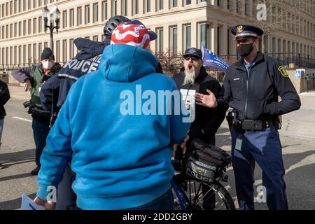 Lansing, Michigan, Stati Uniti. 23 Nov 2020. Un sostenitore del presidente eletto Joe Biden (felpa blu) e del presidente Donald Trump si sono impegnati in una partita gridante mentre il consiglio di amministrazione del Michigan Canvasers si è riunito per decidere se certificare i risultati delle elezioni presidenziali del 2020. La polizia è intervenuta per tenere separati i due. Il Consiglio di Amministrazione ha poi certificato i risultati, che hanno mostrato Biden davanti al presidente Trump di circa 150,000 voti. Credit: Jim West/Alamy Live News Foto Stock