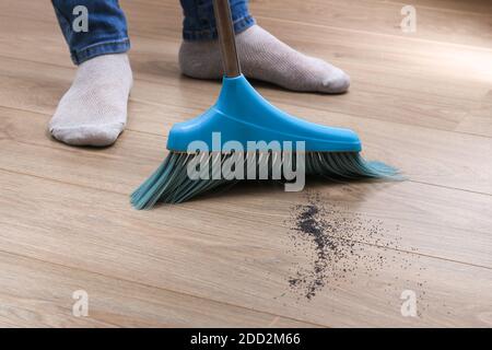 L'uomo spazza i detriti in una paletta blu con una spazzola. Foto Stock