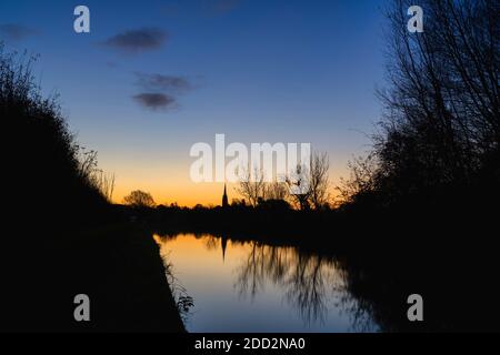 La chiesa di Kings Sutton si riflette nel canale di Oxford all'alba in autunno. Kings Sutton, confine tra Oxfordshire e Northamptonshire, Inghilterra. Silhouette Foto Stock