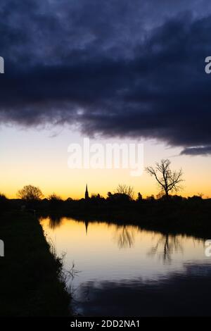 La chiesa di Kings Sutton si riflette nel canale di Oxford all'alba in autunno. Kings Sutton, confine tra Oxfordshire e Northamptonshire, Inghilterra. Silhouette Foto Stock