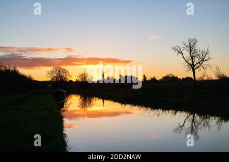 La chiesa di Kings Sutton si riflette nel canale di Oxford all'alba in autunno. Kings Sutton, confine tra Oxfordshire e Northamptonshire, Inghilterra. Silhouette Foto Stock