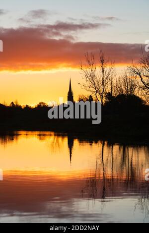 La chiesa di Kings Sutton si riflette nel canale di Oxford all'alba in autunno. Kings Sutton, confine tra Oxfordshire e Northamptonshire, Inghilterra. Silhouette Foto Stock