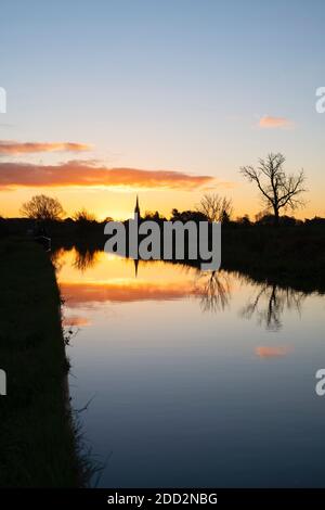 La chiesa di Kings Sutton si riflette nel canale di Oxford all'alba in autunno. Kings Sutton, confine tra Oxfordshire e Northamptonshire, Inghilterra. Silhouette Foto Stock