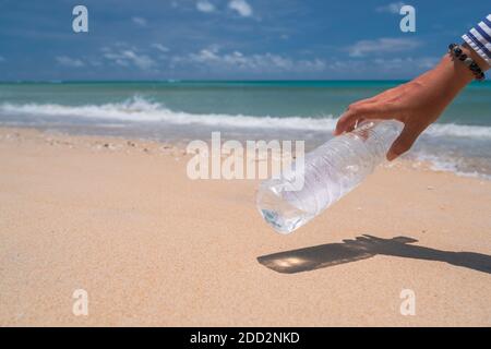 Prendi a mano una bottiglia d'acqua vuota o un cestino presso la bellissima spiaggia. Ambiente problema di riscaldamento globale. Foto Stock