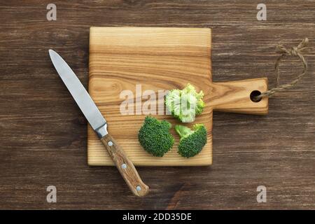 Tavola di legno con infiorescenze di broccoli su tavola di legno, stile rustico. Vista dall'alto, spazio libero Foto Stock