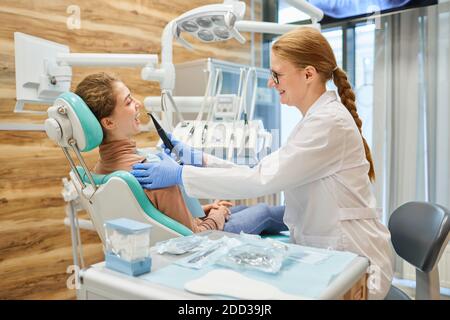 Dentista che fa igiene dentale al paziente alla clinica dentale Foto Stock