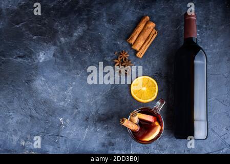 Ricetta di VIN brulé ingredienti su lavagna nera con spazio di testo - bevanda calda di natale o inverno. Bottiglia di vino, miele, arancia, bastoncini di cannella Foto Stock