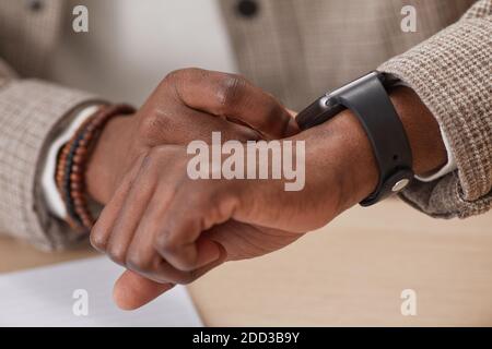 Primo piano di un uomo africano che usa il suo orologio intelligente sul suo mano Foto Stock