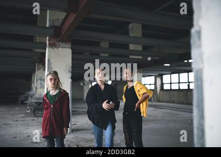 Gruppo di adolescenti gang ragazza al coperto in edificio abbandonato, appendere fuori. Foto Stock