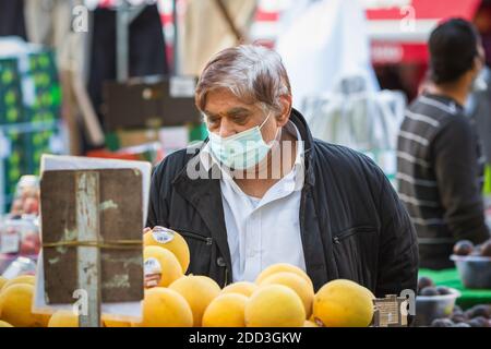 Londra, Regno Unito - 3 novembre 2020 - un uomo asiatico anziano che indossa una maschera mentre fa shopping al mercato di Walthamstow Foto Stock