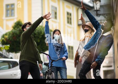 Gruppo di giovani all'aperto in città, saluto. Concetto di coronavirus. Foto Stock