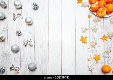 Composizione natalizia con tangerini, decorazioni natalizie d'argento e luci garland e una tazza con marshmallows su sfondo bianco. Nuovo te Foto Stock