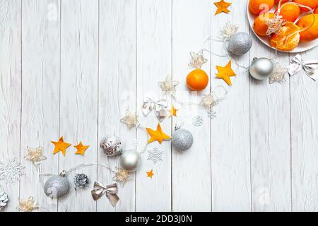 Composizione natalizia con tangerini, decorazioni natalizie d'argento e luci garland e una tazza con marshmallows su sfondo bianco. Nuovo te Foto Stock