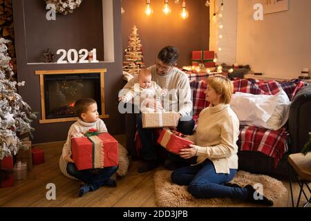 Famiglia apertura regali di Natale vicino albero di Natale in casa decorata, felice anno nuovo 2021 Foto Stock