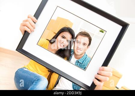 Felice coppia interracial sorridente attraverso cornice dell'immagine dopo il movimento dentro nuova casa Foto Stock