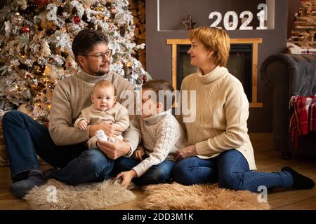 Famiglia vicino albero di Natale in casa decorata, felice anno nuovo 2021 Foto Stock