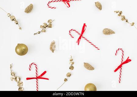 Modello di Natale con decorazione dorata e canne caramelle su bianco. Disposizione piatta, vista dall'alto. Festa di Capodanno Foto Stock