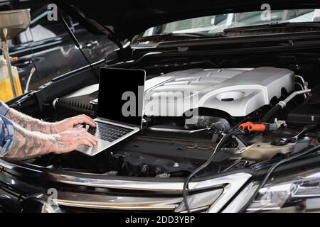 vista parziale del riparatore che effettua la diagnosi del vano motore della vettura Foto Stock