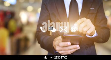CONTATTACI, uomo d'affari mano che tiene smartphone con icona (e-mail, indirizzo, chiamata) Foto Stock
