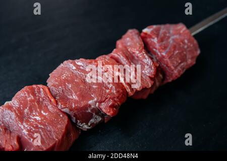 Spiedini di kebab di shish fresco e crudo o carne di shashlik alla griglia. Bistecche di carne di manzo crudo e fresco su sfondo nero. Foto Stock