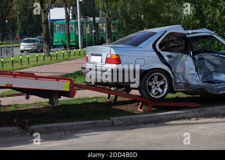 Auto d'argento dopo un terribile incidente d'urto. Impatto frontale e laterale. Foto di concetto di velocità. Il carrello di traino prende la macchina rotta. Foto Stock