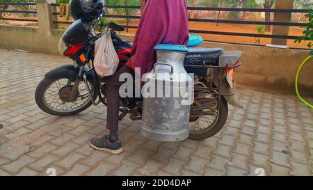 Novembre 2020- Mahroli, Jaipur, India / donna indiana rurale versare il latte in canna di latte al mattino. Foto Stock