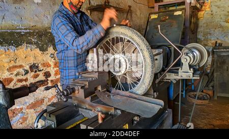 Novembre 2020- Mahroli, Jaipur, India / primo piano vista di pneumatico Bike, montaggio su tornio macchina per la riparazione. Foto Stock