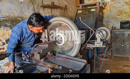 Novembre 2020- Mahroli, Jaipur, India / meccanico indiano professionale che lavora sulla macchina del tornio per riparare il pneumatico della bici. Foto Stock