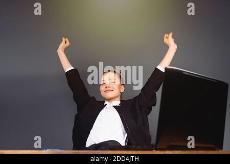 Donna d'affari sorridente che riposa in ufficio contented dopo il lavoro. Sfondo grigio. Foto Stock