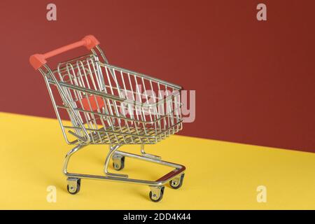 Carrello vuoto su sfondo giallo e marrone colorato. Shopping online o concetto di ecommerce. Spazio di copia, banner. Foto Stock