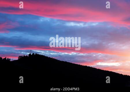 Scenografico e suggestivo tramonto nuvoloso con vista serale sulla località di montagna Villaggio Bukovel in Ucraina con pineta silhouette albero di natale Foto Stock