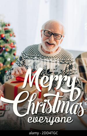 felice uomo anziano che riceve dono da moglie vicino a buon natale tutti a casa Foto Stock