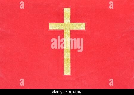 Croce cattolica oro su fondo tessuto rosso. Foto Stock