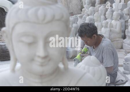 Uomo locale scultura in marmo del Buddha, Amarapura Mandalay, Myanmar (Birmania), l'Asia in febbraio - lavorare in marmo scultura in pietra workshop coperti di polvere Foto Stock