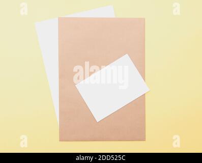 Composizione con fogli bianchi e marroni su sfondo giallo, layout con spazio per il testo, vista dall'alto Foto Stock