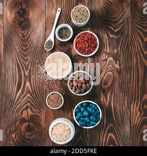 Vari superalimenti in piccola ciotola su tavola di legno.selezione super food.Superfood come mirtillo, chia, cacao crudo fagiolo, goji, semi di canapa, quinoa, riso bruno.Copy spazio per text.Top vista o piatto Lay.Square Foto Stock