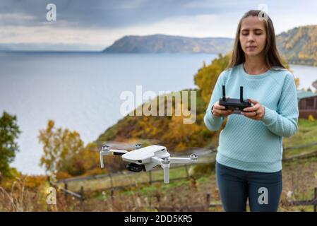 Figura sfocata di ragazza controlla un drone su sfondo sfocato autunno. Confetto messa a fuoco morbida Foto Stock