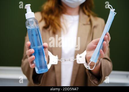 Insegnante di scuola incatenato con manette stand con disinfettante e maschera medica, virus problema concetto Foto Stock