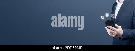 CONTATTACI. Uomo d'affari che tiene cellulare con posta, telefono, icona e-mail. Cutomer supporto concetto. Copia spazio. Sfondo blu Foto Stock