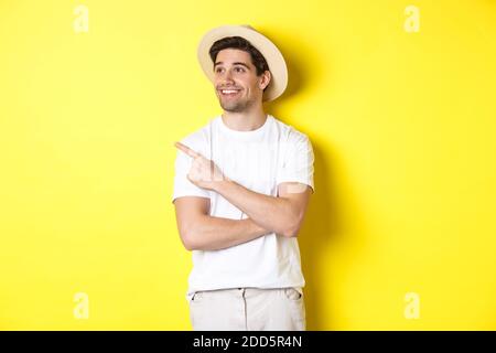 Concetto di turismo e stile di vita. Happy man turista che controlla promo, guardando soddisfatto e puntando il dito sul logo angolo in alto a sinistra, giallo Foto Stock