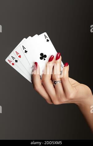 Quattro assi che giocano le carte in mano della donna. Giocatore con combinazione di quads di poker. Eleganti mani femminili con manicure rossa sui chiodi. Foto Stock