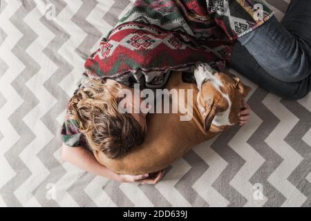 Donna si distende con un cane e la abbraccia. Supporto emotivo, depressione e stress con animali domestici durante il blocco e rimanere a casa ordini Foto Stock