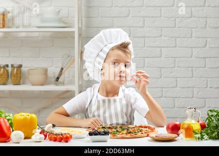 Bambina in cappello da chef e un grembiule che cucina la pizza