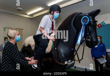 East Lothian, Scozia, Regno Unito, NHS Lothian & Muirfield Riding Therapy celebrano 10 anni di ippoterapia: Il fisioterapista Heather Falconer ha aperto la strada al Children’s Therapeutic Riding Service, che offre un'equitazione terapeutica gratuita a bambini e adulti con disabilità. Il servizio è stato il primo in Scozia. Oreo, un cavallo meccanico, permette ai giovani di ricevere una divertente fisioterapia. Charlie Kay, di 13 anni che ha partecipato sin dall'inizio, si trova a cavallo del simulatore meccanico Racewood Foto Stock