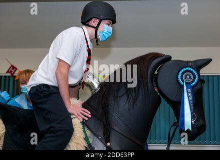 East Lothian, Scozia, Regno Unito, NHS Lothian & Muirfield Riding Therapy celebrano 10 anni di ippoterapia: Il fisioterapista Heather Falconer ha aperto la strada al Children’s Therapeutic Riding Service, che offre un'equitazione terapeutica gratuita a bambini e adulti con disabilità. Il servizio è stato il primo in Scozia. Oreo, un cavallo meccanico, permette ai giovani di ricevere una divertente fisioterapia. Charlie Kay, di 13 anni che ha partecipato sin dall'inizio, si trova a cavallo del simulatore meccanico Racewood Foto Stock