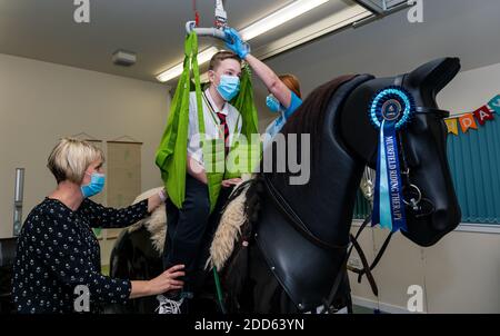 East Lothian, Scozia, Regno Unito, NHS Lothian & Muirfield Riding Therapy celebrano 10 anni di ippoterapia: Il fisioterapista Heather Falconer ha aperto la strada al Children’s Therapeutic Riding Service, che offre un'equitazione terapeutica gratuita a bambini e adulti con disabilità. Il servizio è stato il primo in Scozia. Oreo, un cavallo meccanico, permette ai giovani di ricevere una divertente fisioterapia. Charlie Kay, di 13 anni che ha partecipato sin dall'inizio, è issato sul simulatore meccanico di cavalli Racewood Foto Stock