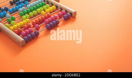 Scuola abacus con perle colorate su sfondo di colore arancione, vista ravvicinata, spazio copia. Conteggio di apprendimento dei bambini, concetto di classe matematica dei bambini Foto Stock