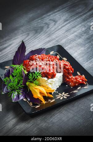 Tradizionale pepe balcanico spalmato - ajvar, servito con formaggio di capra ed erbe fresche (fuoco selettivo) Foto Stock