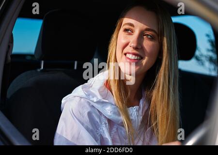 Giovane donna in viaggio di strada vacanza guida e guardando fuori della vetrina dell'auto a noleggio Foto Stock