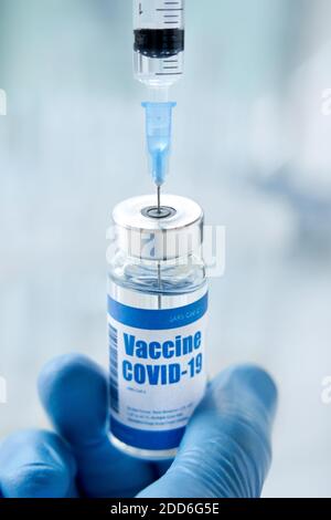 Medico o scienziato di sesso maschile che tiene una siringa che prende il vaccino covid 19 dal flaconcino. Foto Stock